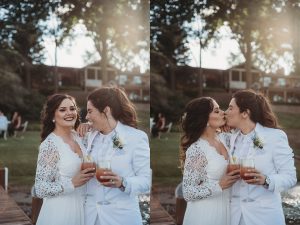 two brides in white kissing at sunset