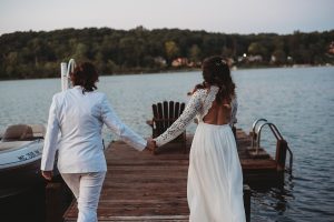 two brides walking on a dock at sunset