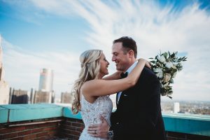 bride and groom laughing and smiling on top of guardian building detroit