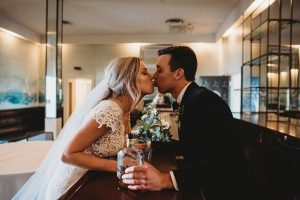 bride and groom kissing over bar belle isle boat house