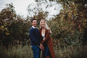 couple laughing in a field engagement pictures