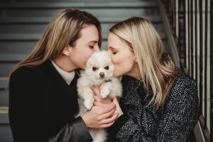 Same sex lesbian couple kissing a Pomeranian puppy engagement photos
