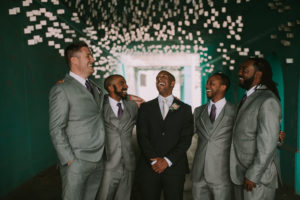 Groom and groomsmen laughing in teal tunnel downtown Detroit