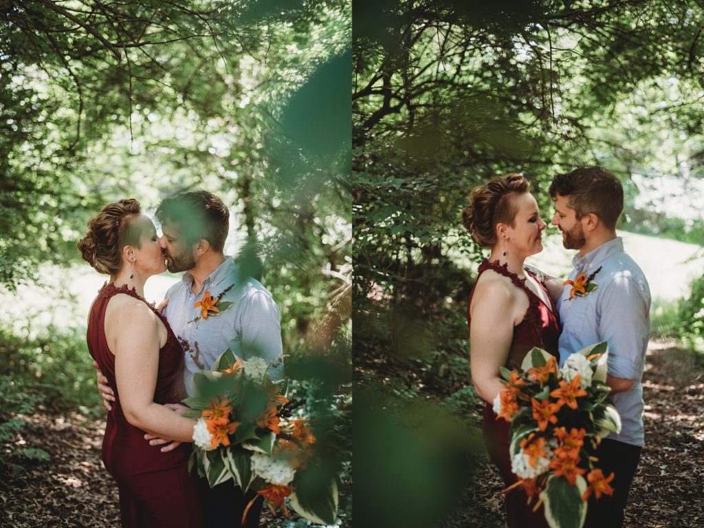 bride in a maroon dress with orange flowers and groom in a blue shirt smiling and laughing in the woods