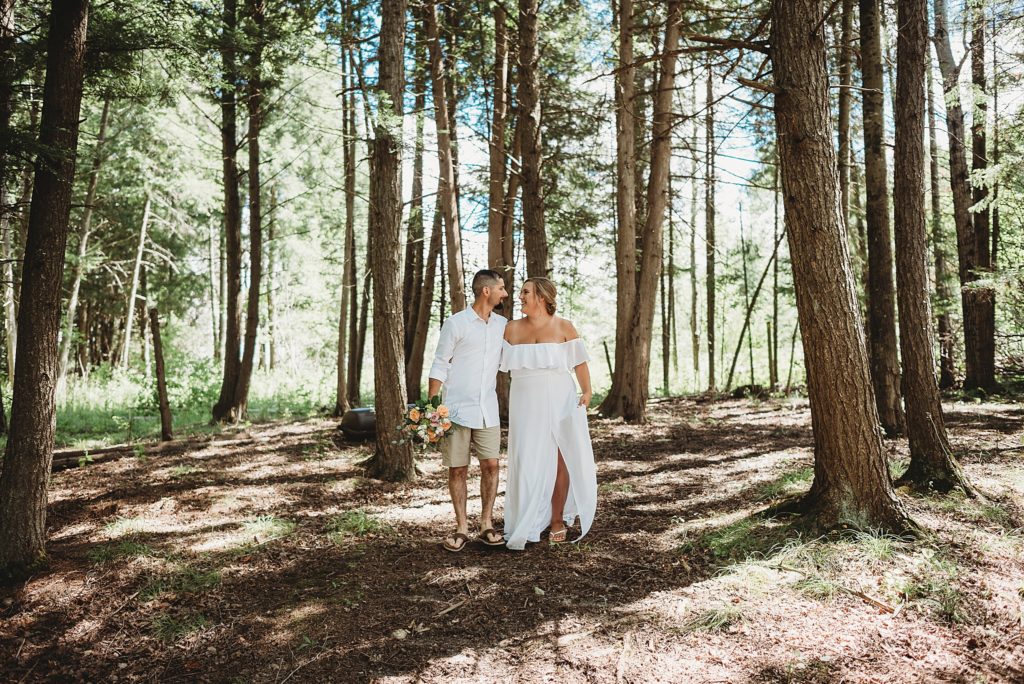bride and groom walking and laughing through the woods northern michiagn 