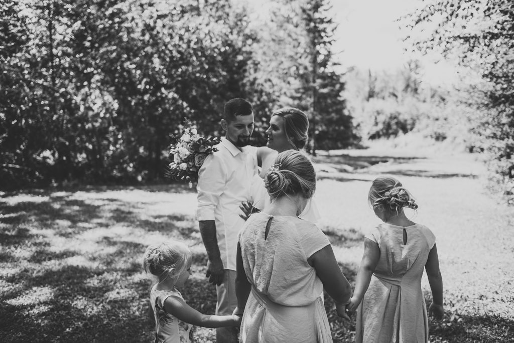 bride and groom and kids walking and laughing in a back yard in the summer