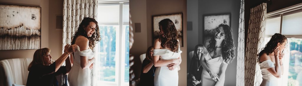 brides mom helping her get into her wedding dress and smiling by a window