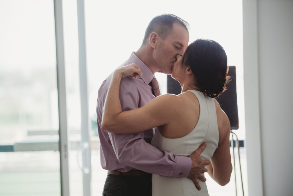 bride and groom kissing during their first dance in their living room during the pandemic