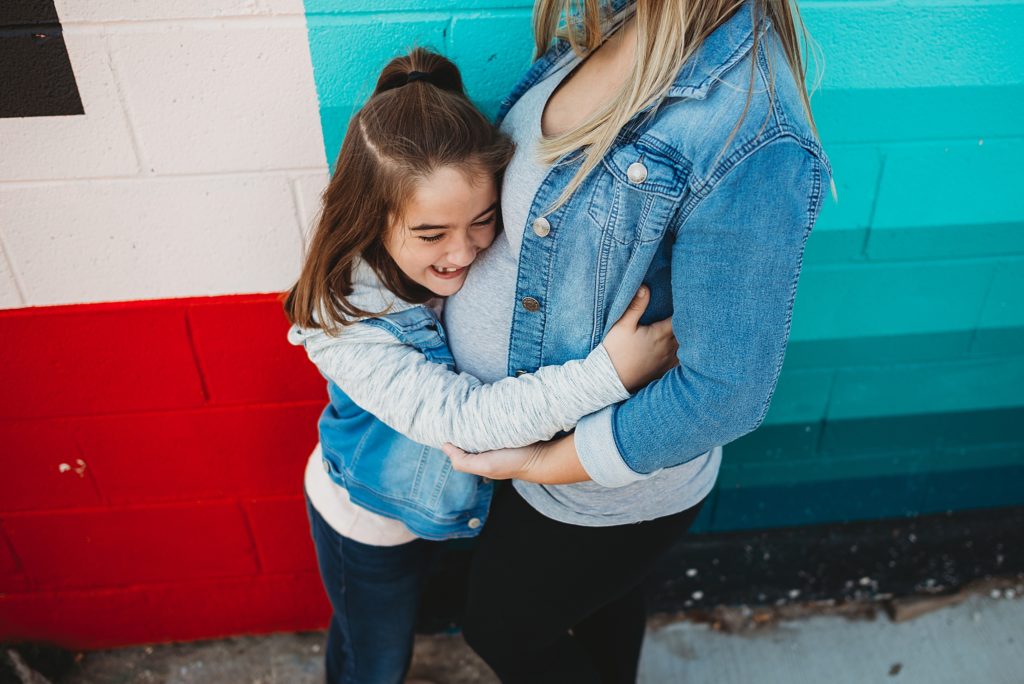 little girl hugging moms belly